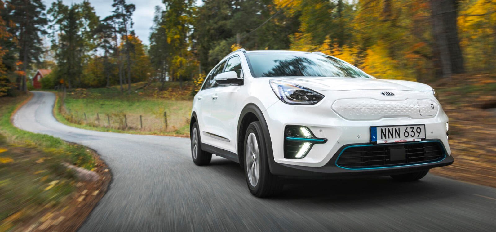 En vit Kia Soul kör nerför en landsväg. (AI text)