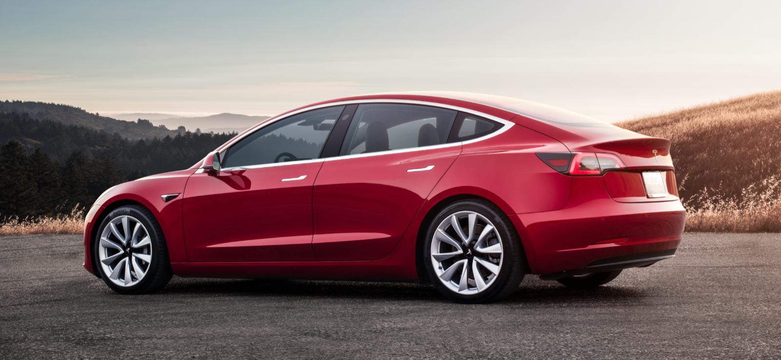En röd Tesla Model 3 parkerad på en backe. (AI text)