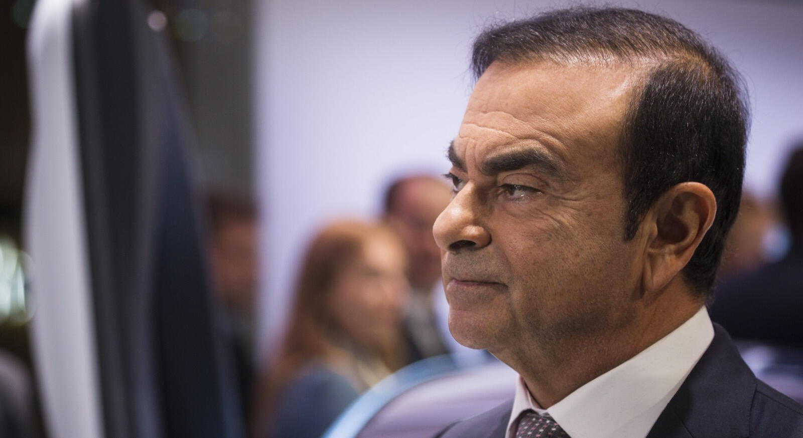 En man i kostym och slips står framför en bil. (AI text)