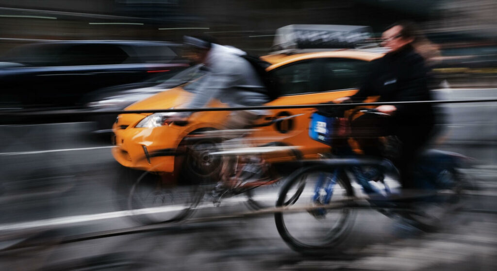 En man cyklar och en man kör bil på en stadsgata. (AI text)