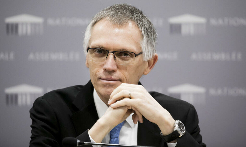 En man i kostym och slips sitter vid ett skrivbord. (AI text)