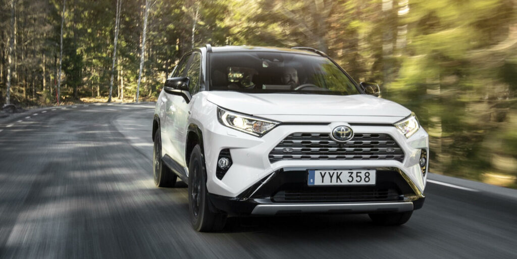 En vit Toyota RAV4 kör längs en landsväg. (AI text)
