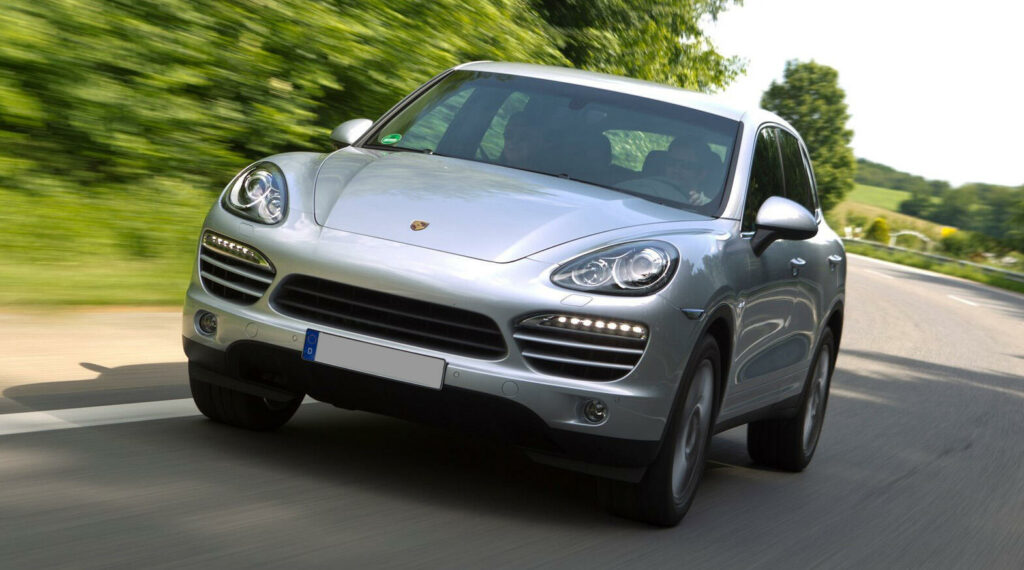 En silverfärgad Porsche Cayenne kör längs en landsväg. (AI text)
