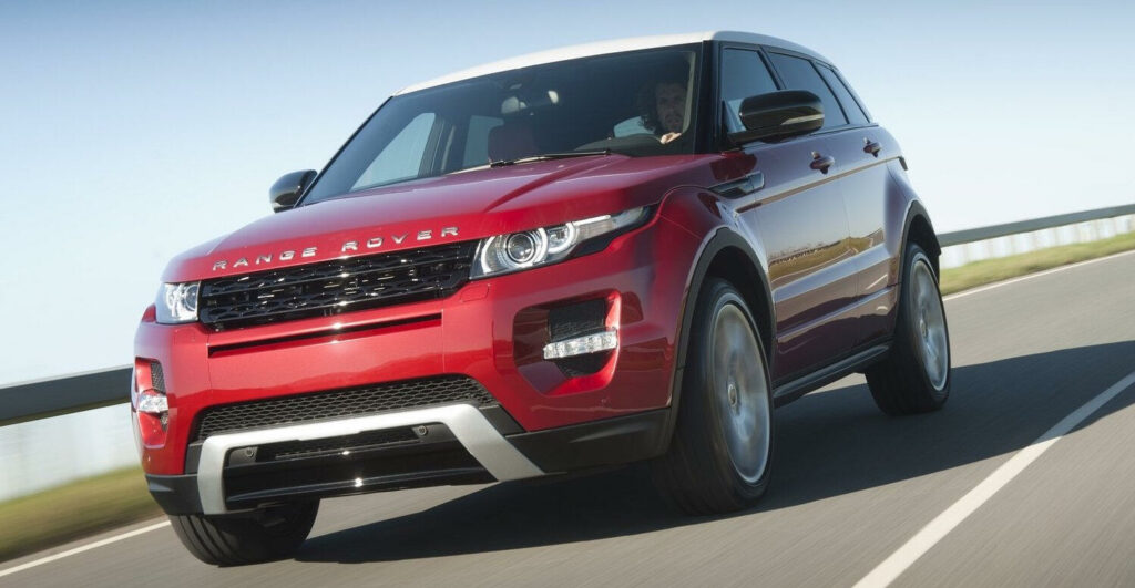 En röd Range Rover Evoque kör längs en landsväg. (AI text)