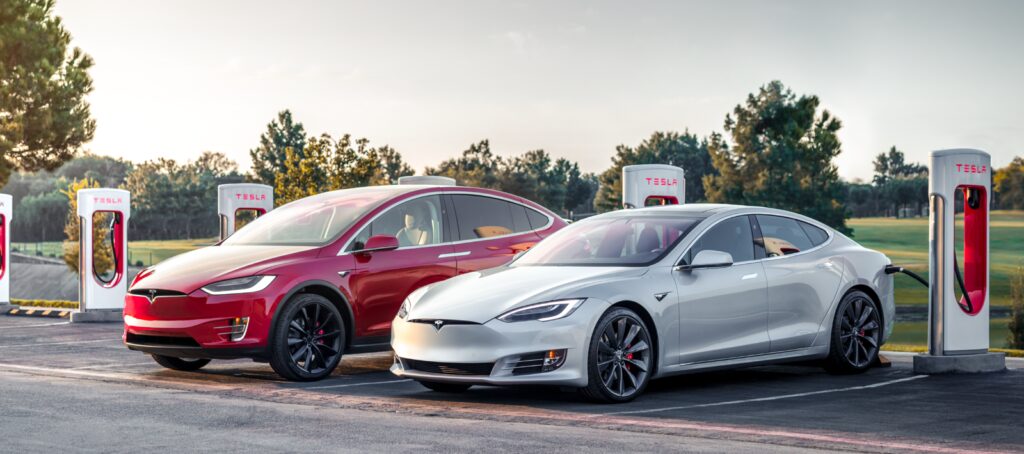 Tesla Model S och Tesla Model X parkerade vid en laddstation. (AI text)