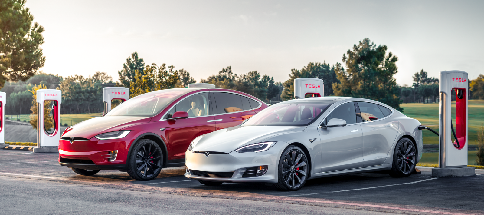 Tesla Model S och Tesla Model X parkerade vid en laddstation. (AI text)