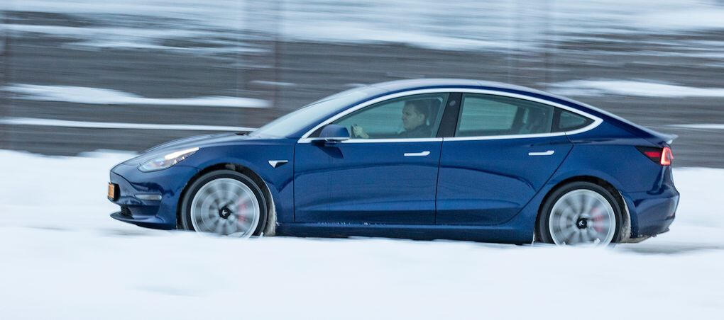 Tesla Model 3 kör genom snön. (AI text)