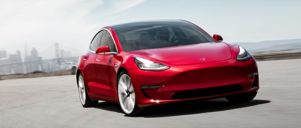 En Tesla Model 3 kör på en stadsgata. (AI text)