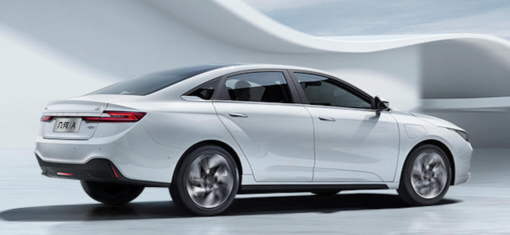 En vit bil parkerad i en vit yta. (AI text)