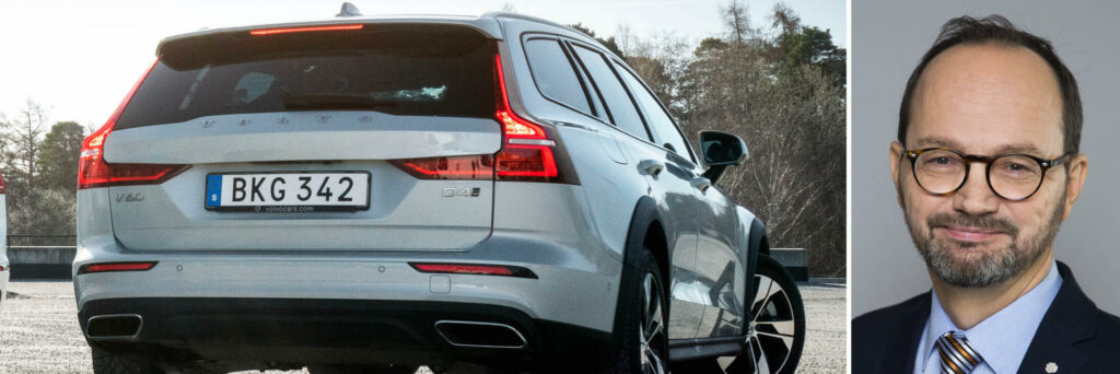 En man i kostym och slips står bredvid en Volvo XC90 SUV. (AI text)