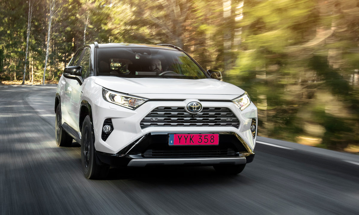 En vit Toyota RAV4 kör nedför en väg. (AI text)