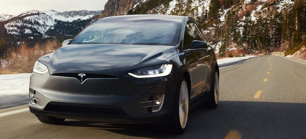 Tesla Model X kör nerför en bergsväg. (AI text)