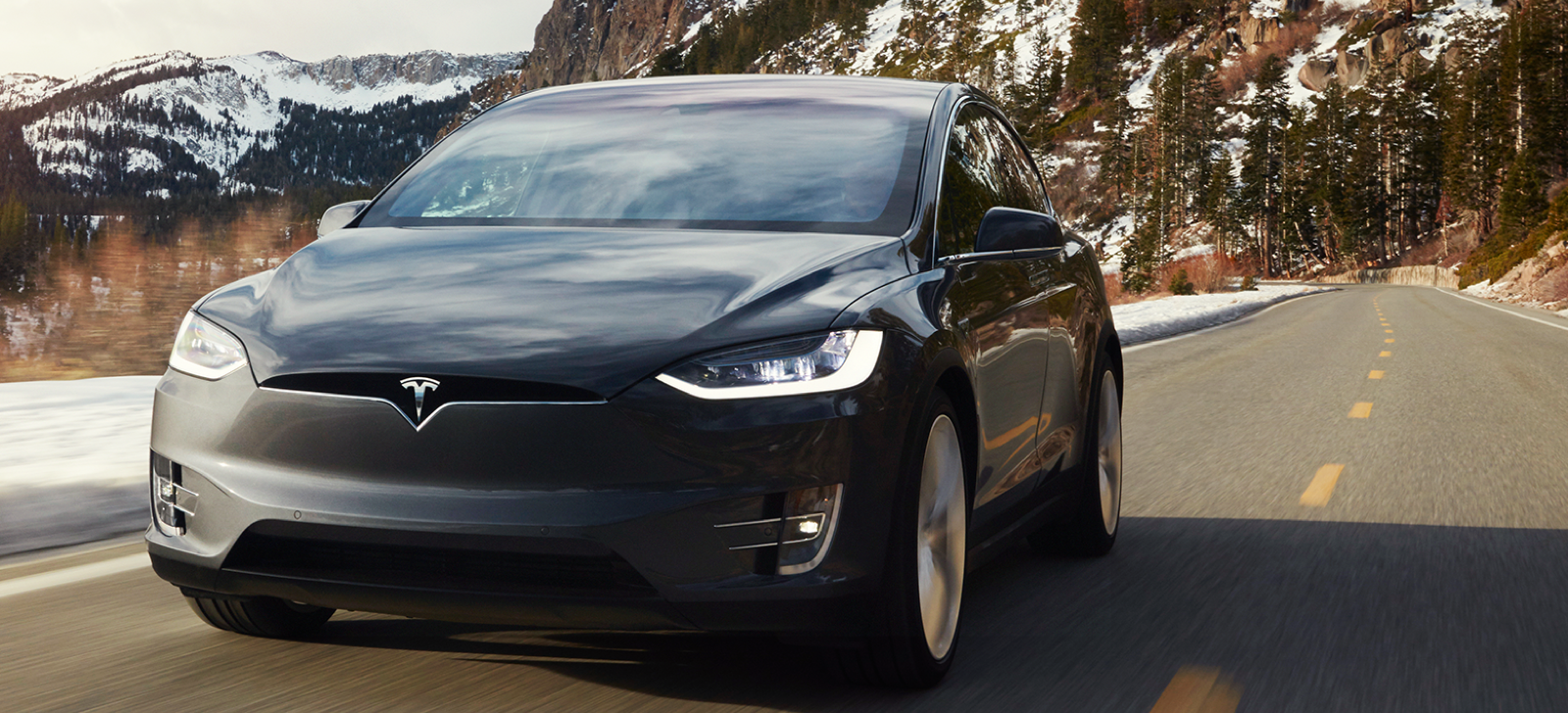 Tesla Model X kör nerför en bergsväg. (AI text)