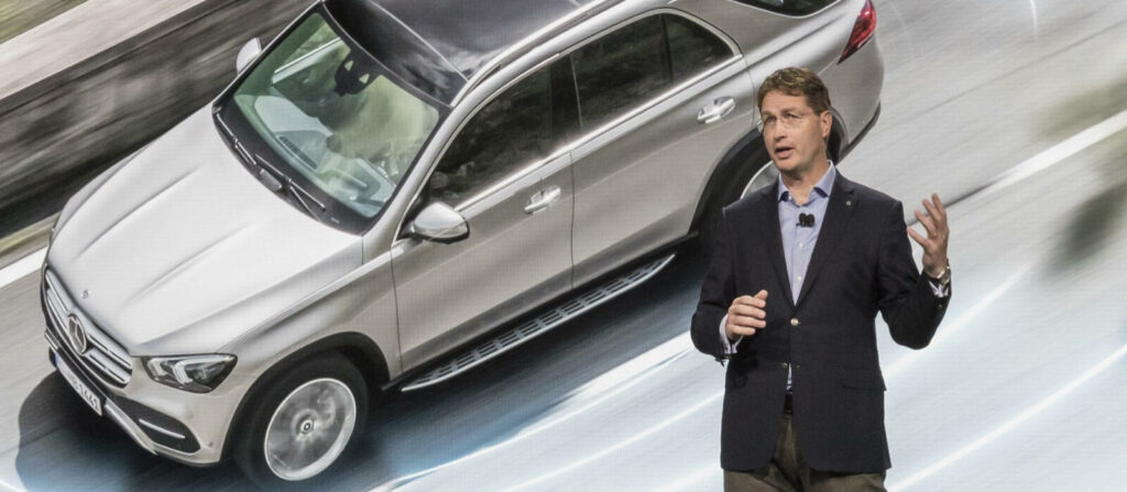 En man i kostym står bredvid en bil. (AI text)