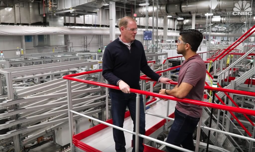 Två män står i en fabrik. (AI text)