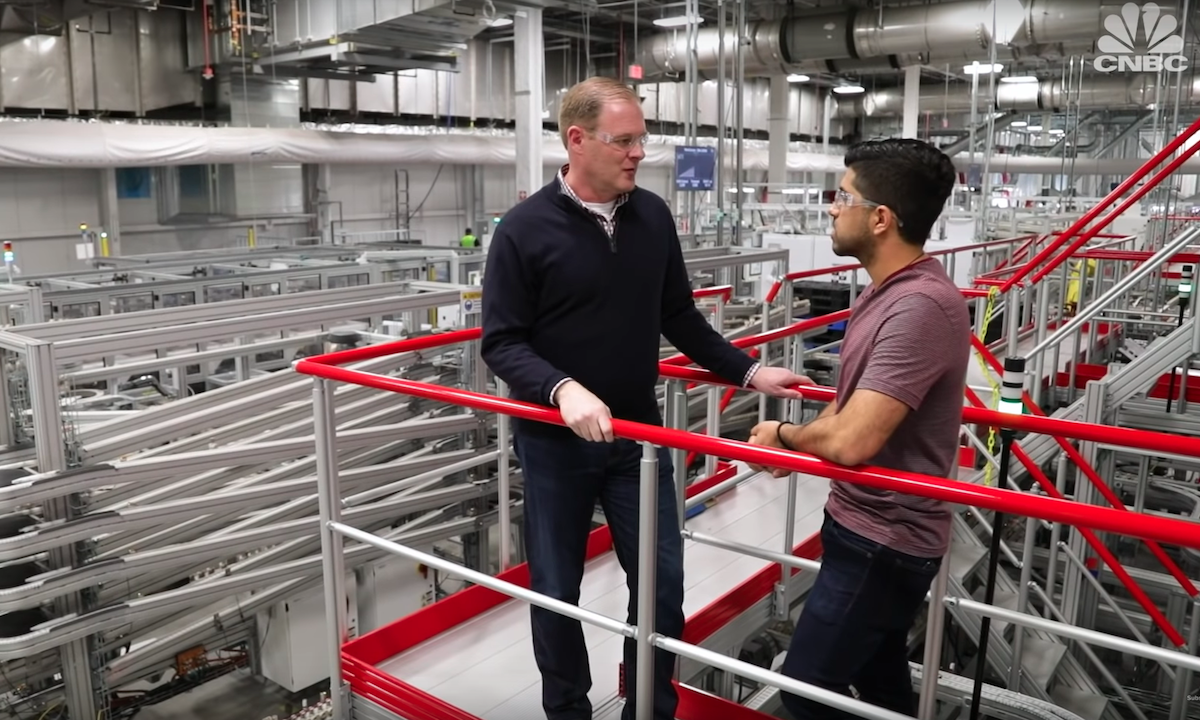 Två män står i en fabrik. (AI text)