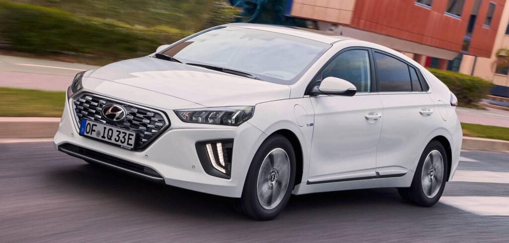 En vit Hyundai Ioniq kör nedför en stadsgata. (AI text)