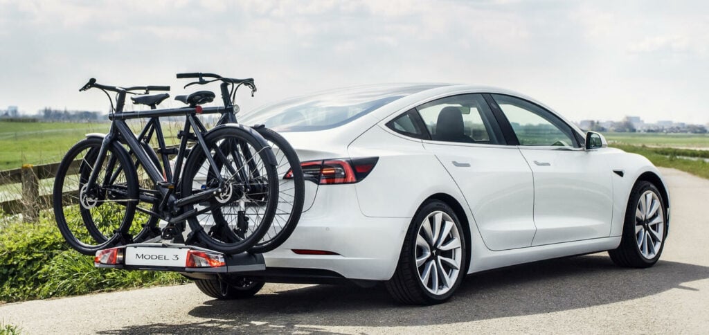 Tesla Model 3 med cykelväxel på vägen (AI text)