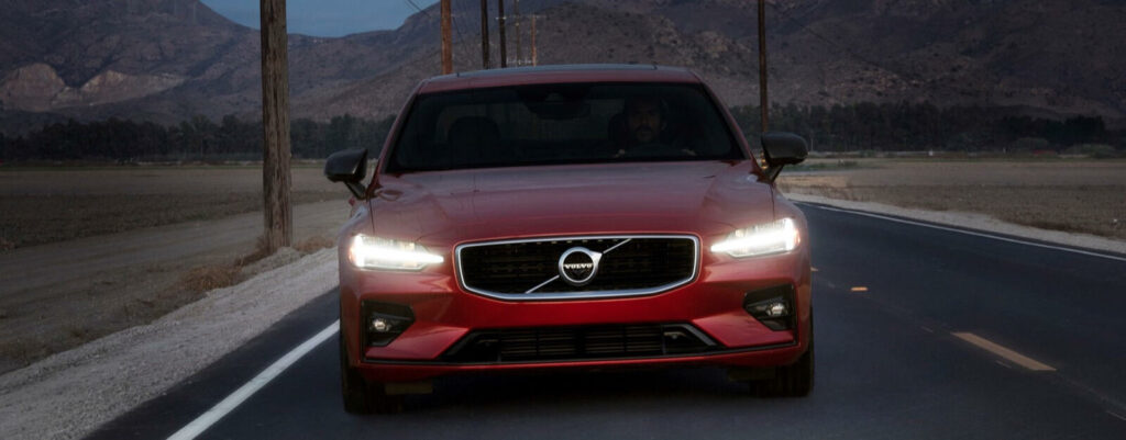 En röd Volvo XC90 kör nerför en landsväg. (AI text)