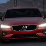 En röd Volvo XC90 kör nerför en landsväg. (AI text)