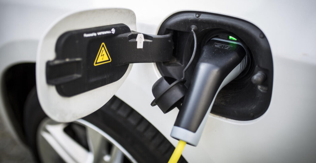 En vit bil är uppkopplad till en elladdare. (AI text)