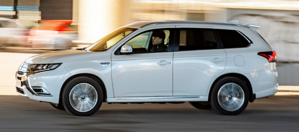 En vit SUV kör ner en gata. (AI text)