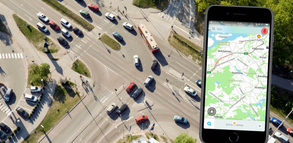 En bil kör nerför en gata med en telefon i handen. (AI text)