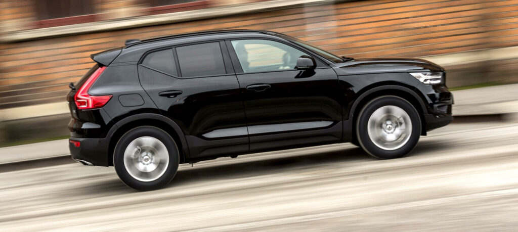 En svart Volvo XC90 SUV kör nedför en gata. (AI text)