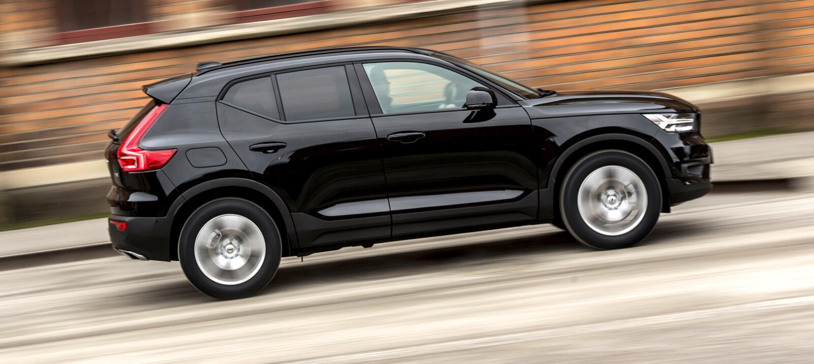 En svart Volvo XC90 SUV kör nedför en gata. (AI text)