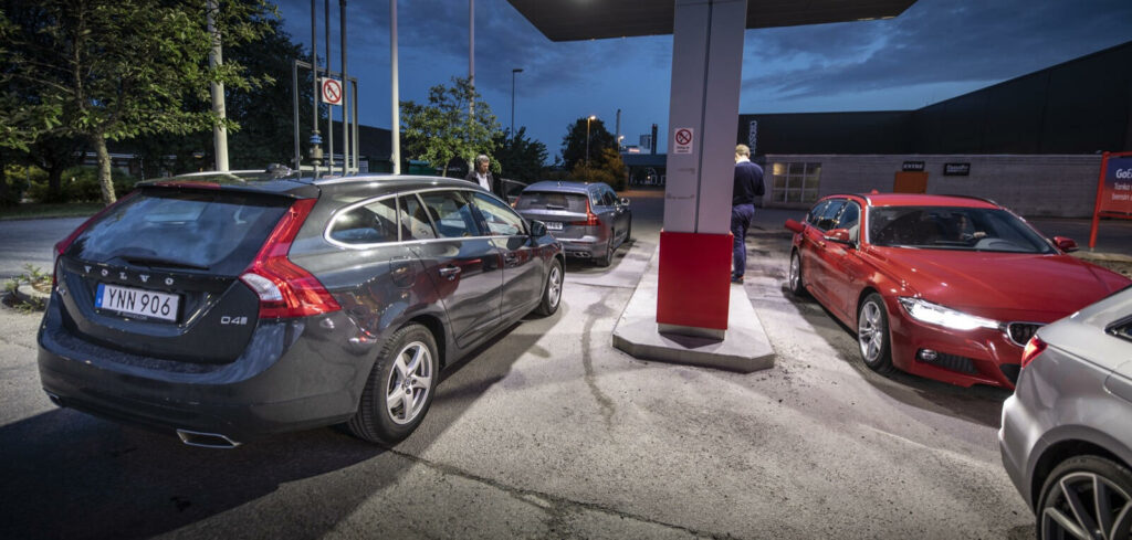 En grupp bilar parkerade vid en bensinstation. (AI text)