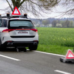 En bil kör nedför en landsväg med en kon i vägen. (AI text)