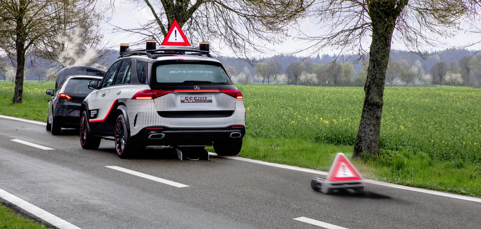 En bil kör nedför en landsväg med en kon i vägen. (AI text)