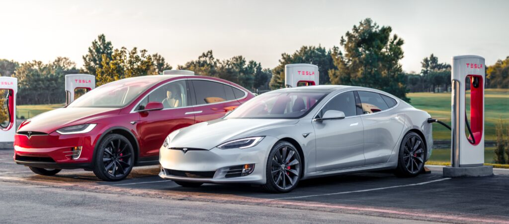 Tesla Model S och Tesla Model X parkerade vid en laddstation. (AI text)