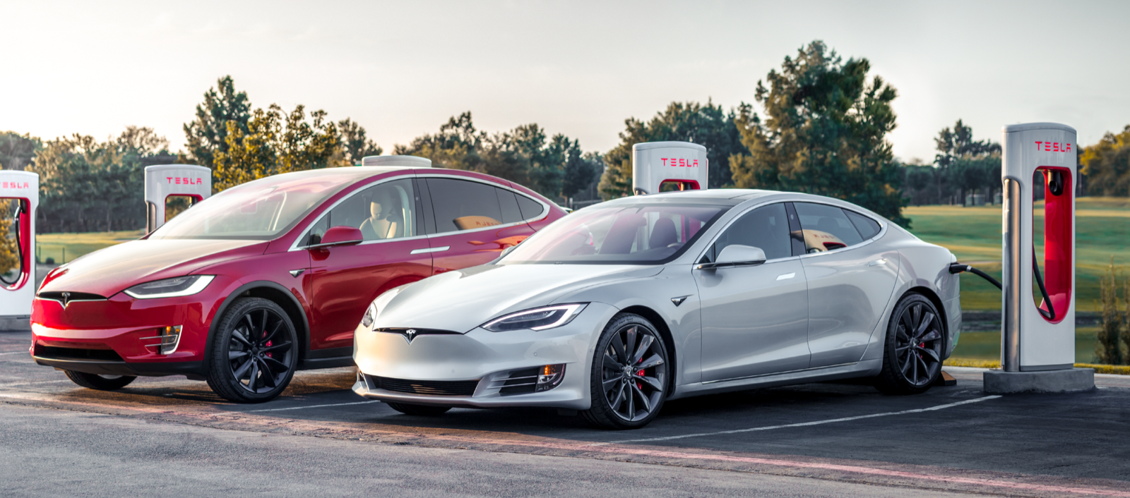 Tesla Model S och Tesla Model X parkerade vid en laddstation. (AI text)