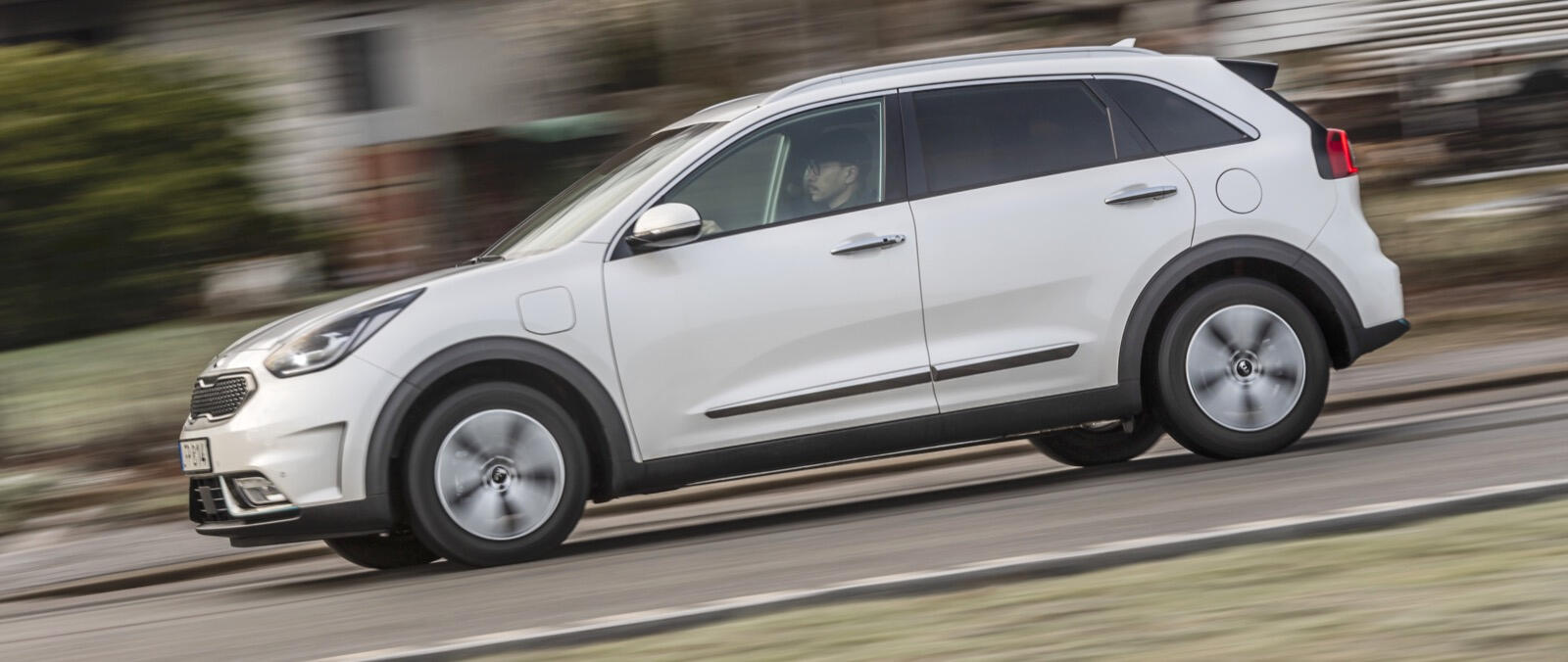 En vit Kia Niro kör nedför en landsväg. (AI text)