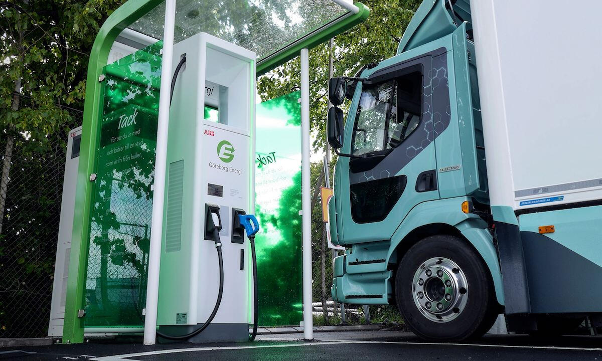 En grön lastbil parkerad vid en elbil laddstation. (AI text)
