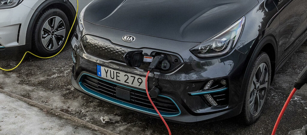 En Kia Rio som laddas upp i en elbilsladdare. (AI text)