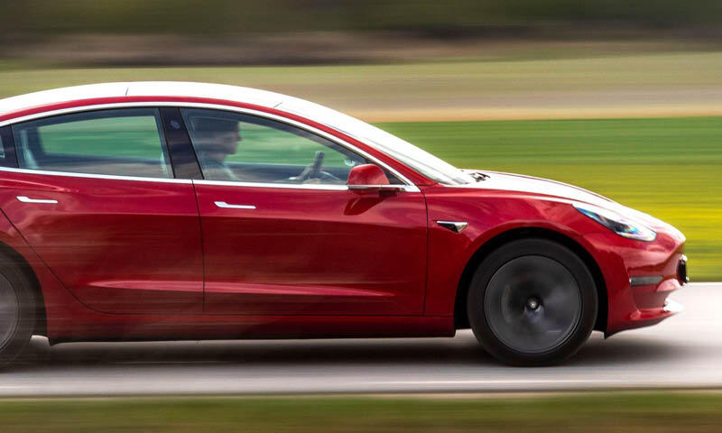 En Tesla Model 3 kör på en väg. (AI text)