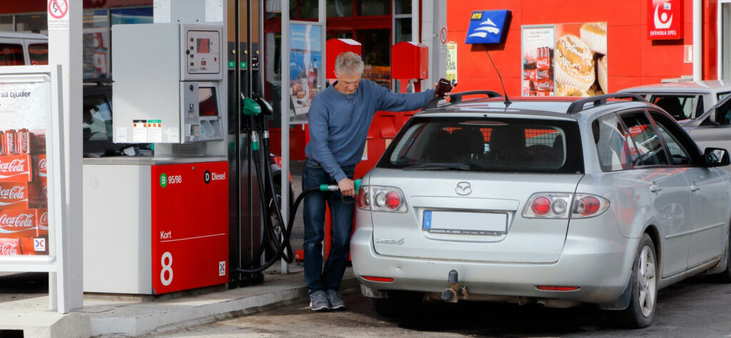 En man tankar sin bil vid en bensinstation. (AI text)