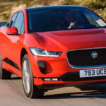 En röd jaguar i Pace kör nedför en landsväg. (AI text)
