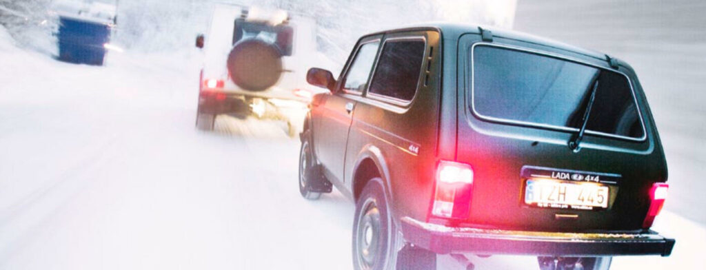 En bil kör genom en snöig gata. (AI text)