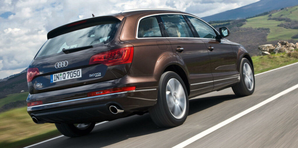 En Audi Q7 SUV kör längs en landsväg. (AI text)