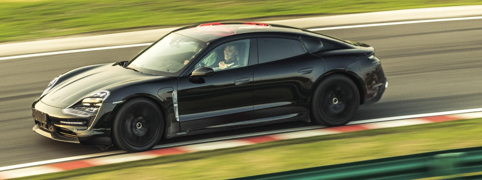 En svart Porsche Cayman GTS kör på en bana. (AI text)