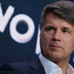 En man i kostym och slips talar vid en konferens. (AI text)