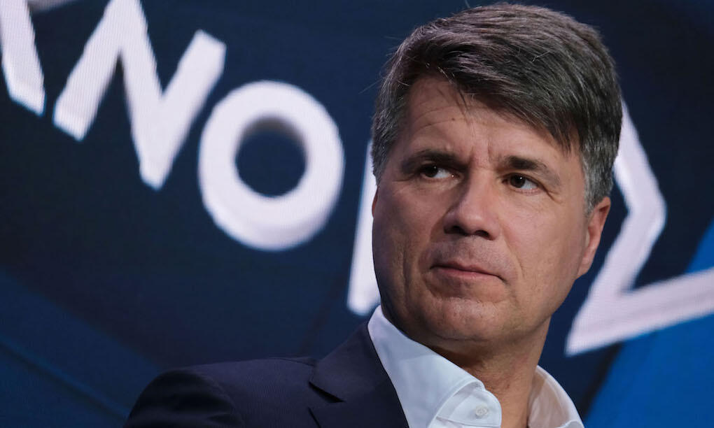 En man i kostym och slips talar vid en konferens. (AI text)