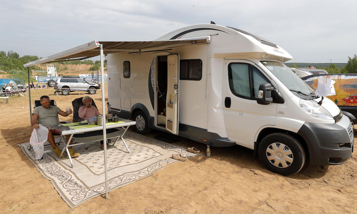 En campingvagn parkerad på en grusplan. (AI text)