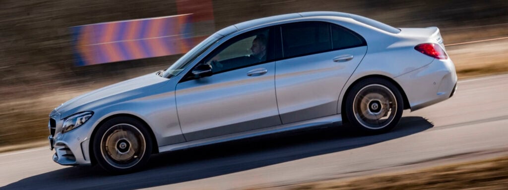 En Mercedes C-klass sedan kör på en väg. (AI text)
