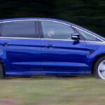 En blå Ford Galaxy kör längs en landsväg. (AI text)