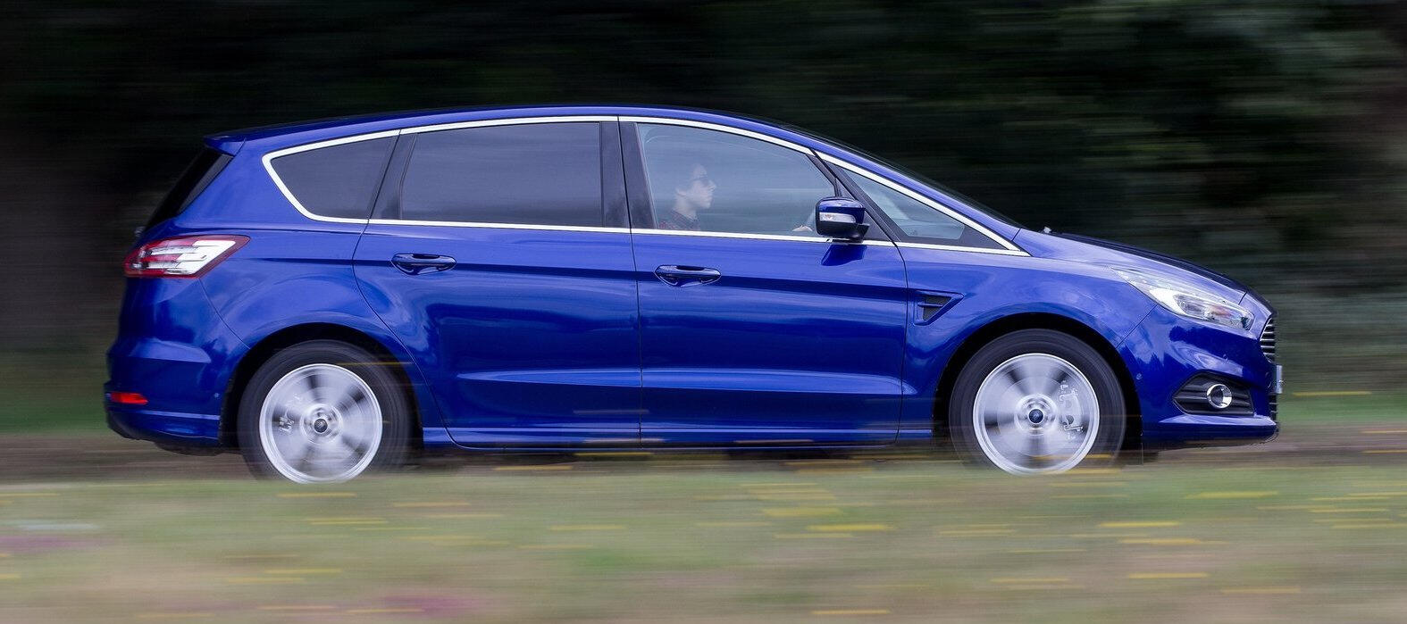 En blå Ford Galaxy kör längs en landsväg. (AI text)
