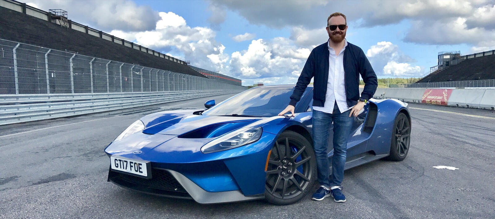 En man står bredvid en blå sportbil. (AI text)